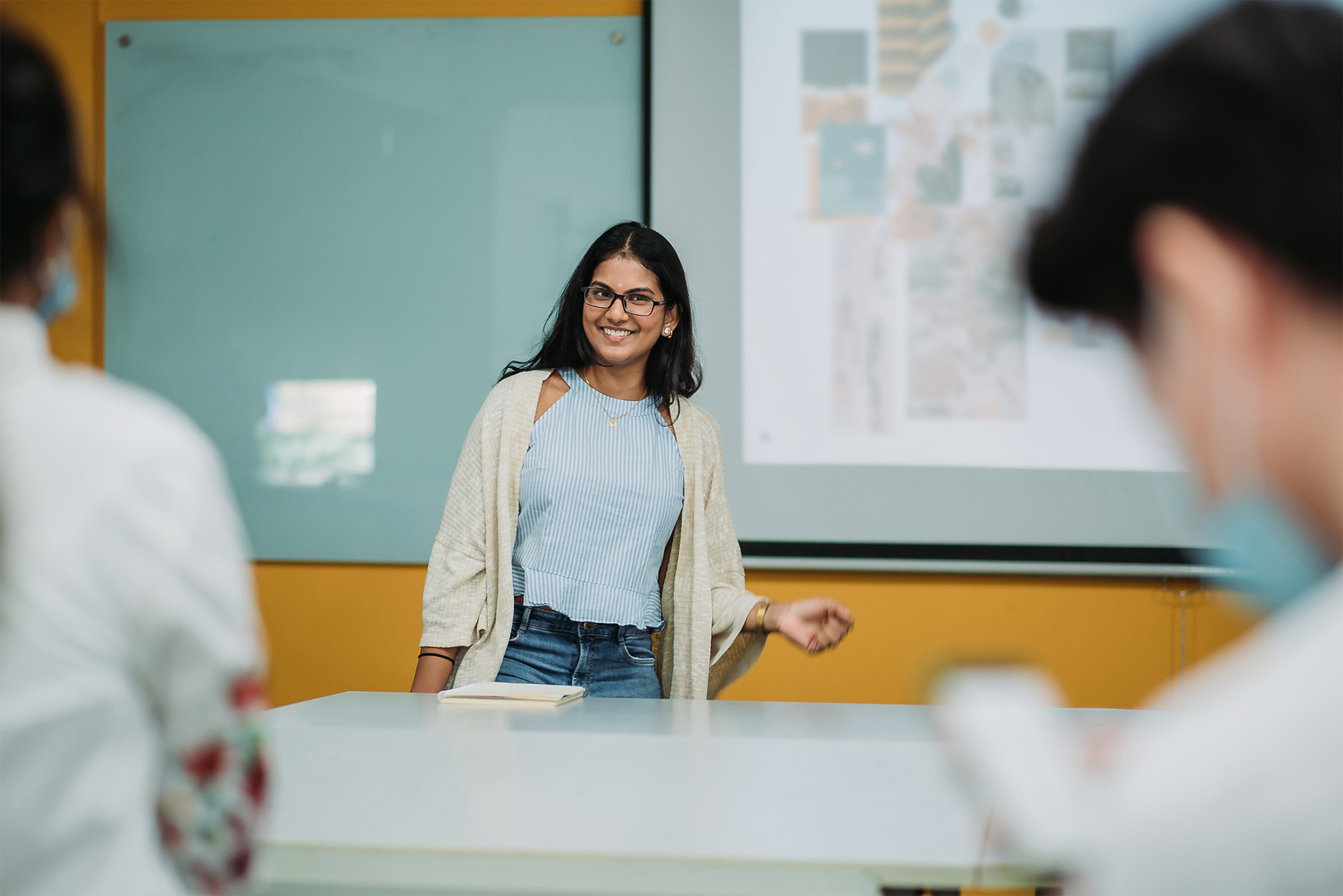 instructor at head of classroom speaks animatedly to fellow professors and teaching assistants during an in-service.